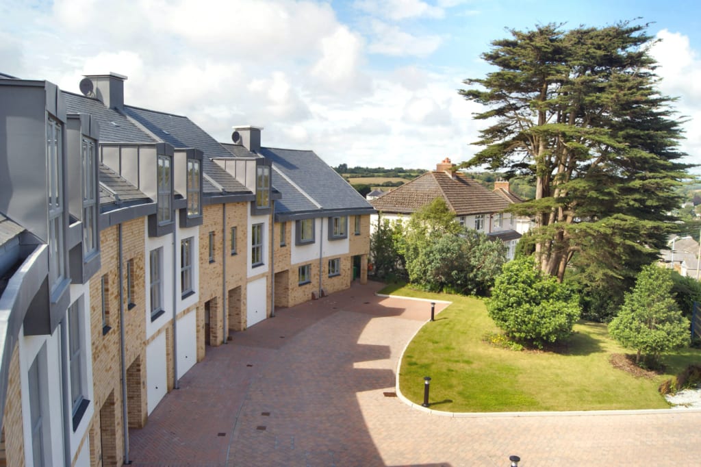 Curved terraced housing development with large windows, stone walls and communal garden