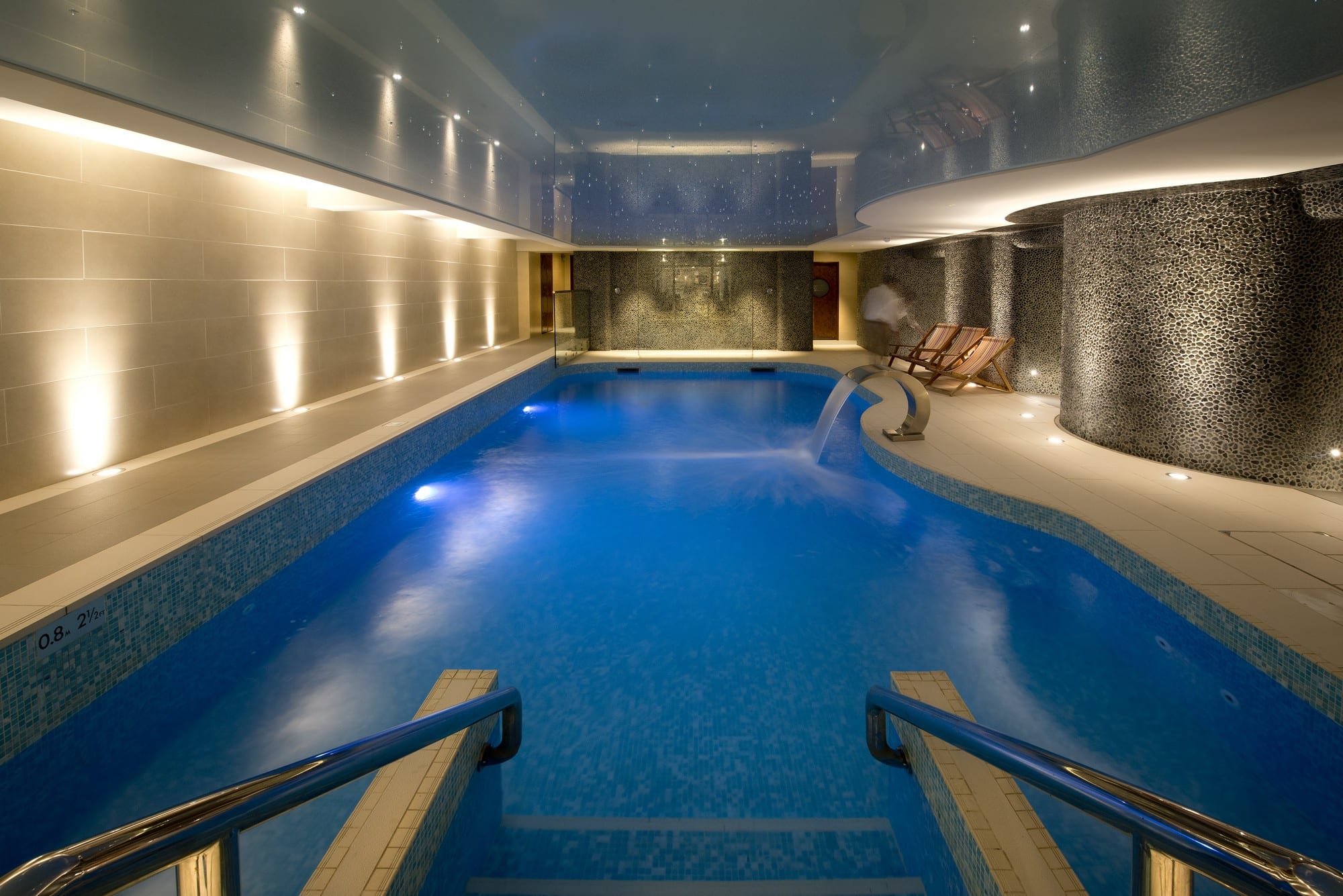 Inside spa pool with stone walls and water feature.