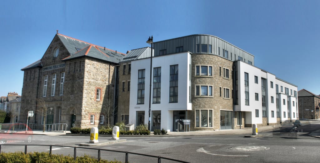 Large redeveloped old school building with stone walls by a road.